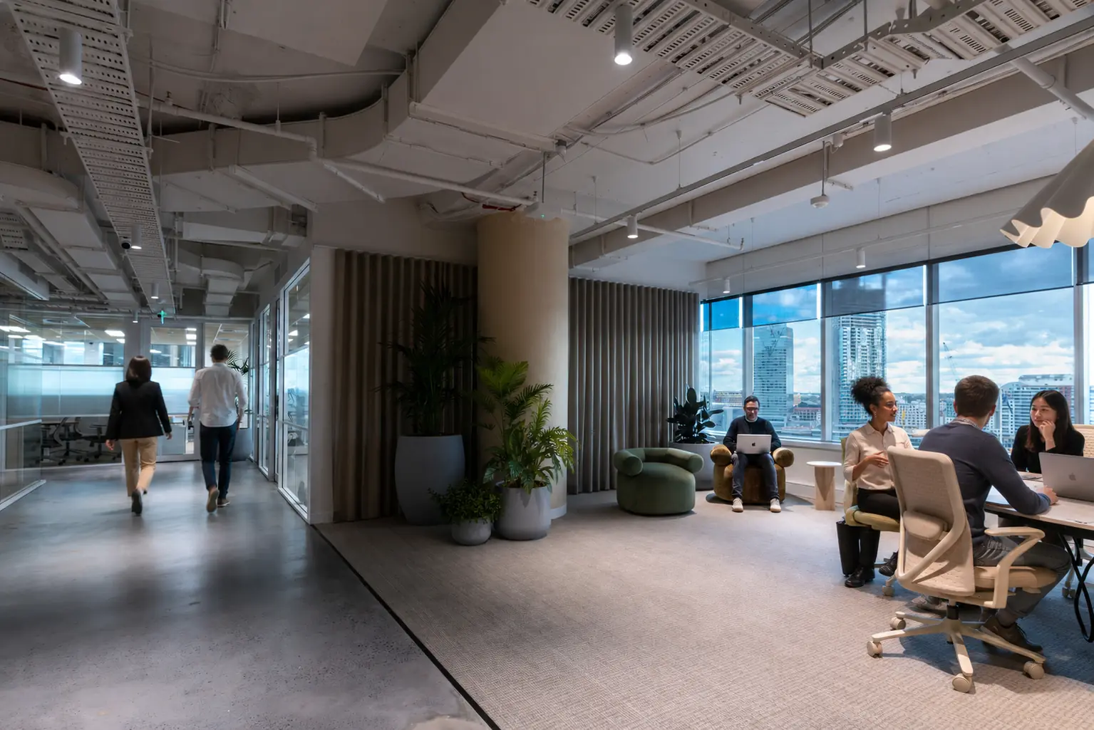 Creative agency team collaborating in a flexible office space with greenery and client-ready meeting areas
