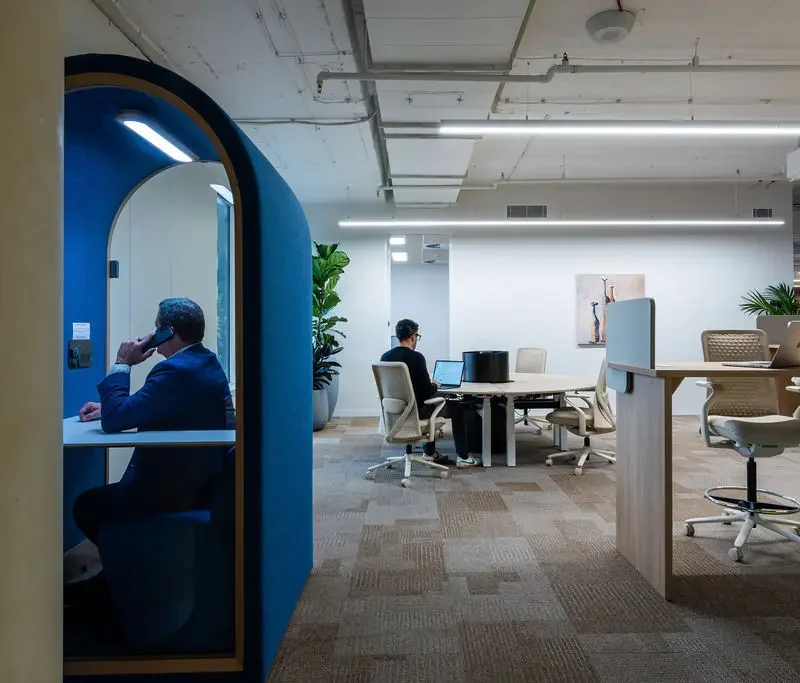 Creative agency team collaborating in flexible office space with project tables and quiet work zones