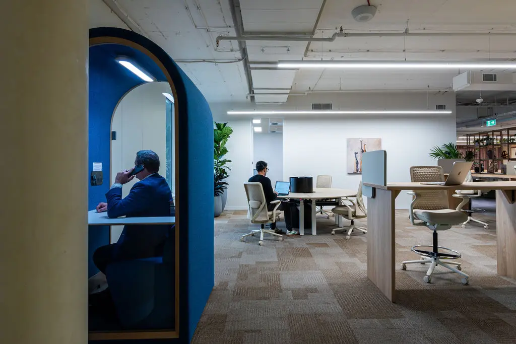 Creative agency team collaborating in flexible office space with project tables and quiet work zones